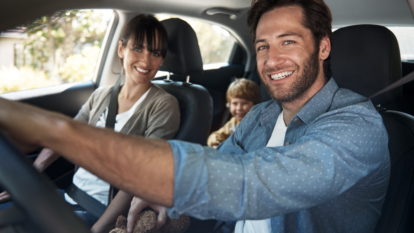 Family smiling inside SUV during everyday drive together.