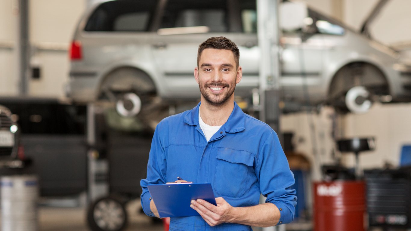 Automotive technician performing winter vehicle inspection in service department.