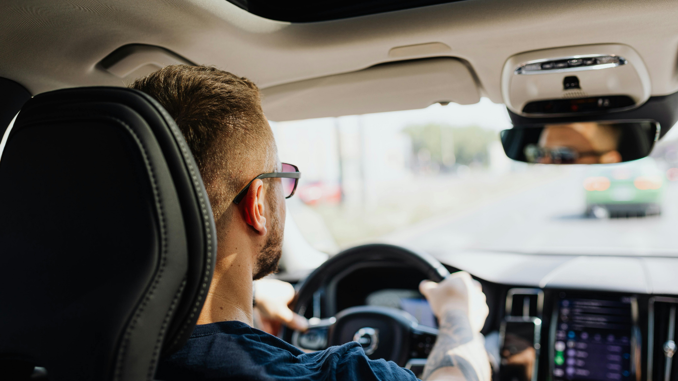 Driver behind the wheel of a vehicle during daytime commute, representing reliable transportation after loan approval.