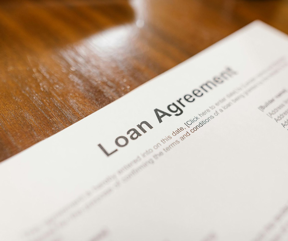 A close-up of a document entitled ‘Loan Agreement’ on a wooden table.